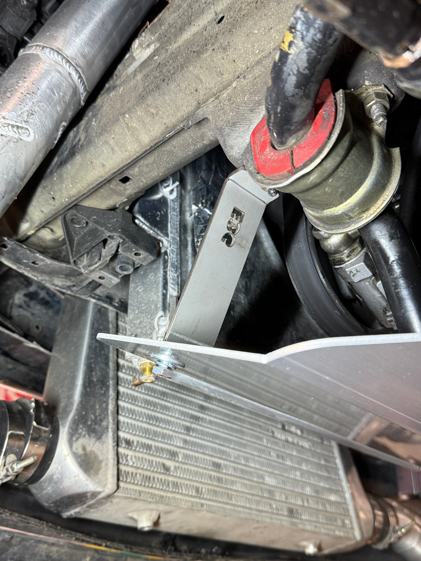 Close-up of a car's radiator and surrounding components with a wrench.