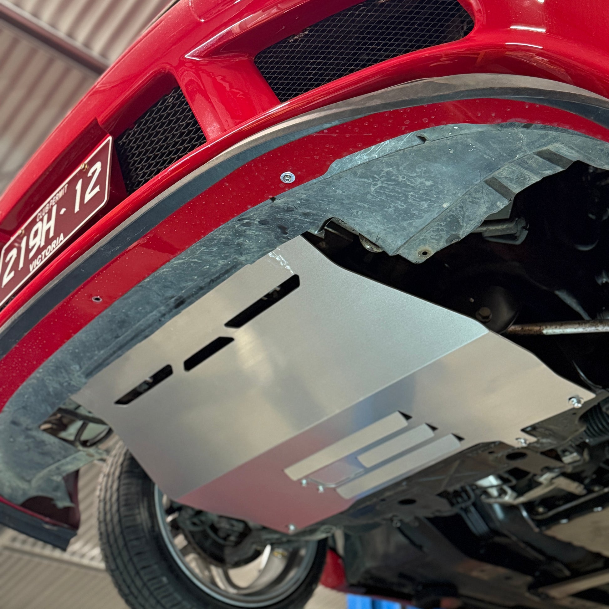 Close-up of a red vehicle's undercarriage with a metal guard.