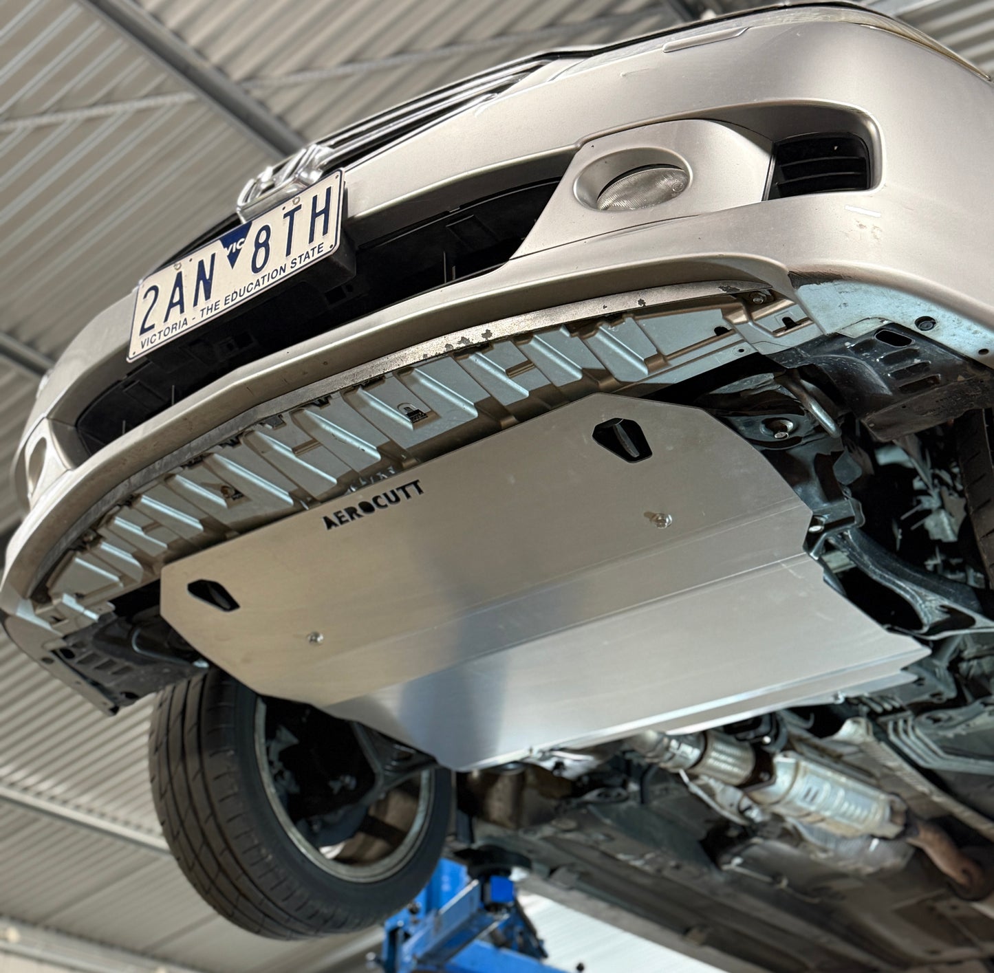 Car undercarriage with a protective metal plate in a garage setting