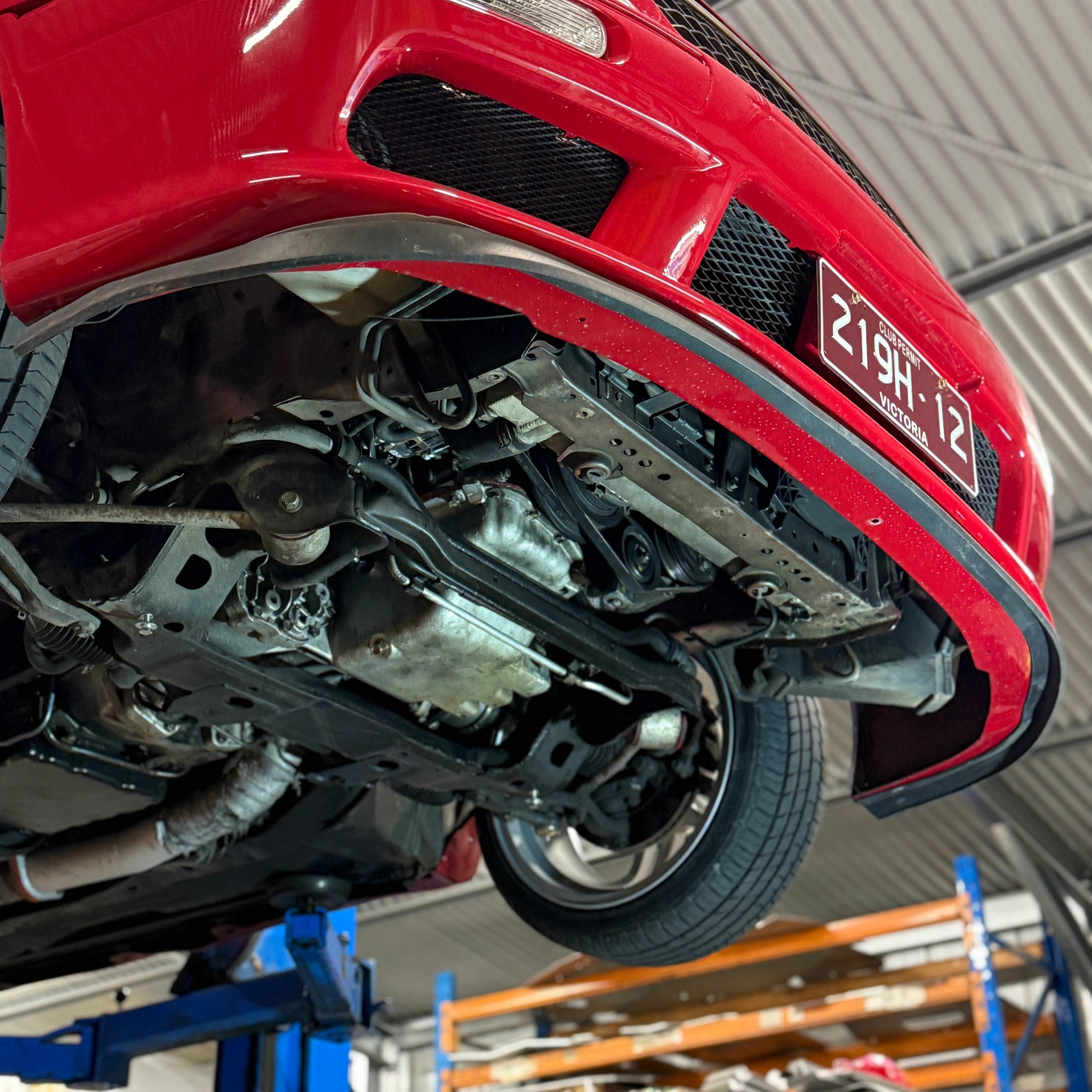 Red car elevated on a lift in a garage