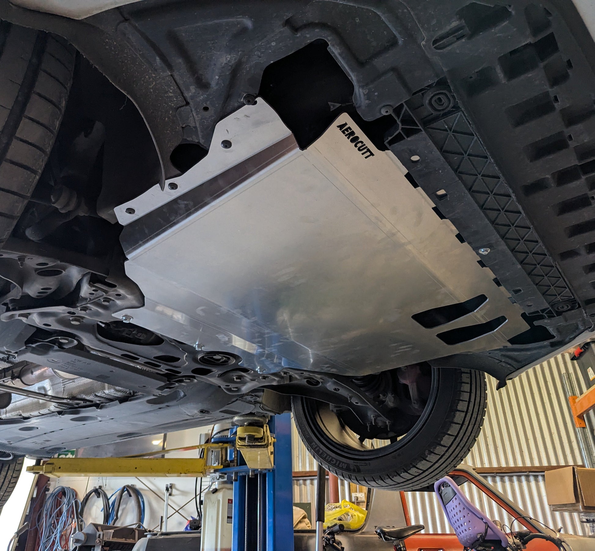 Car undercarriage with a protective skid plate on a lift in a garage. SKODA OCTAVIA UNDERTRAY REPLACEMENT PANEL ON CAR, ENGINE PROTECTION PLATE SKODA OCTAVIA MQB 