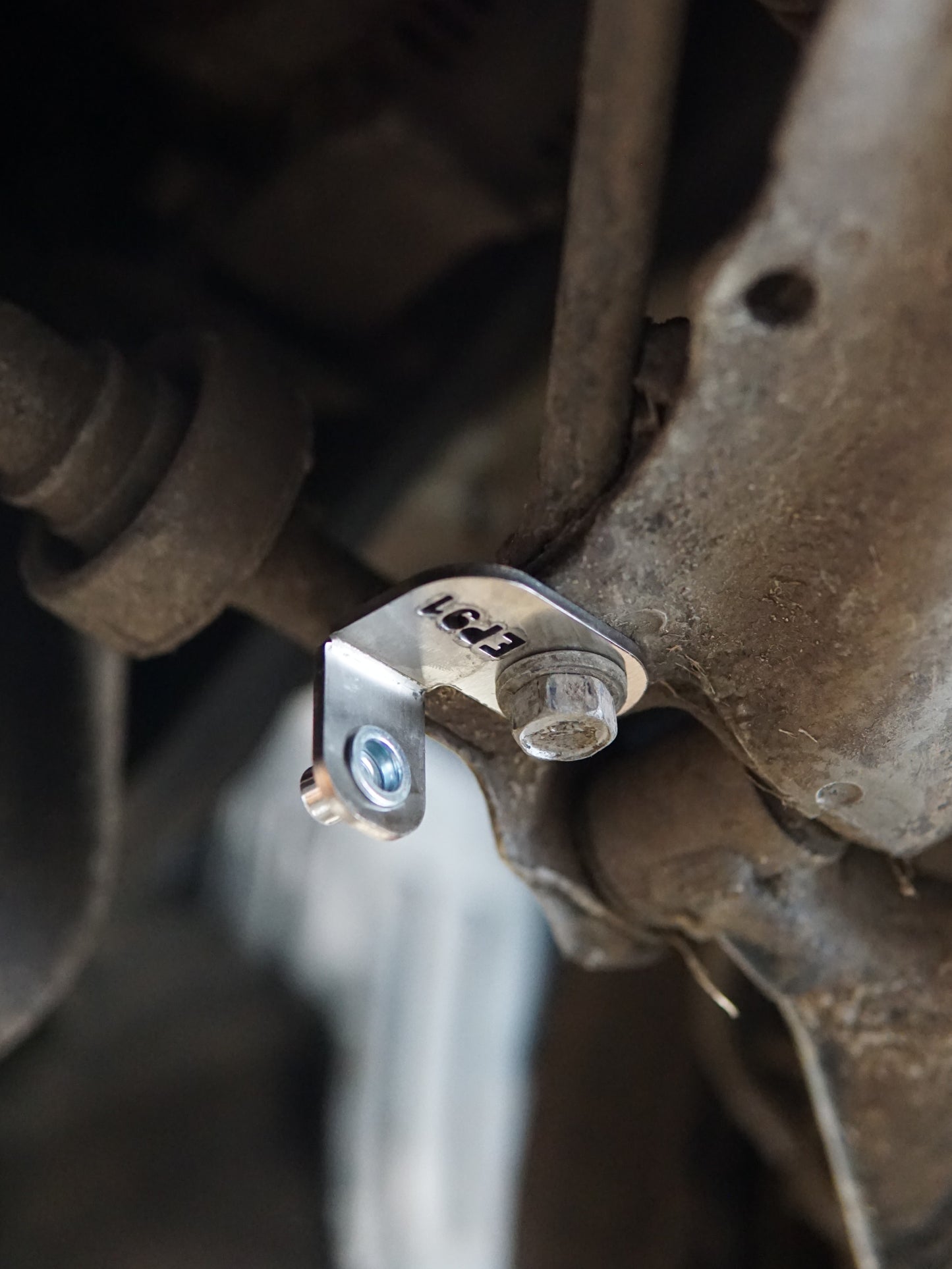 Close-up of a metal skid plate bracket on a Toyota Starlet EP91