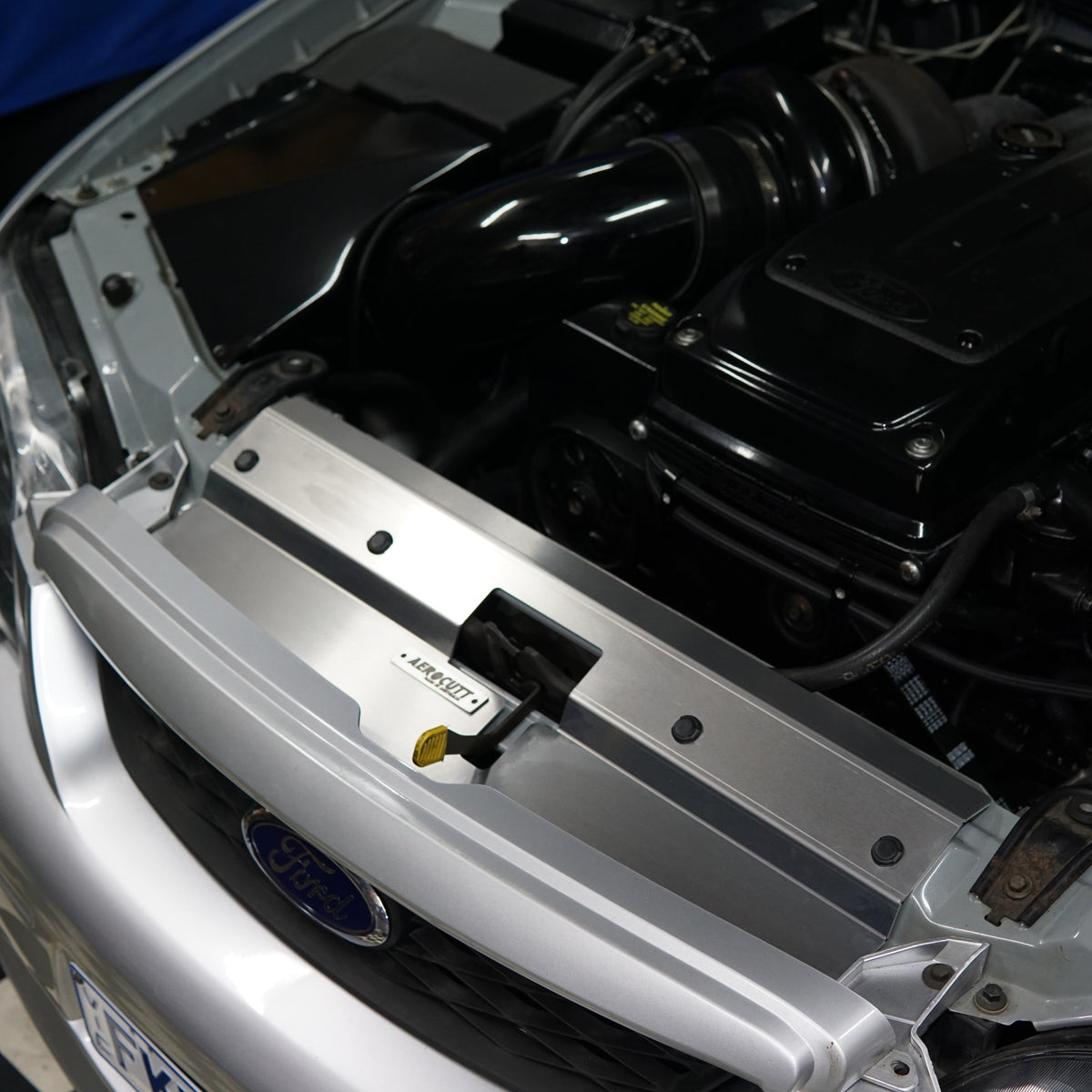 A close up of a Ford Falcon BA/BF engine bay with an Aerocutt aluminium replacment air diversion plate/cooling panel