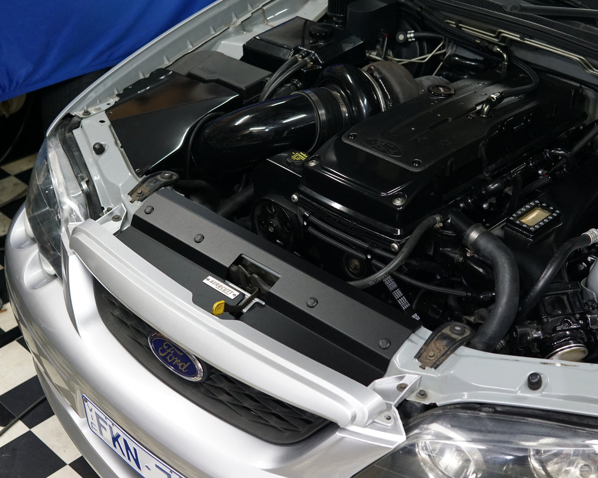 A close up of a Ford Falcon BA/BF engine bay with an Aerocutt aluminium replacment air diversion plate/cooling panel in powder coated black