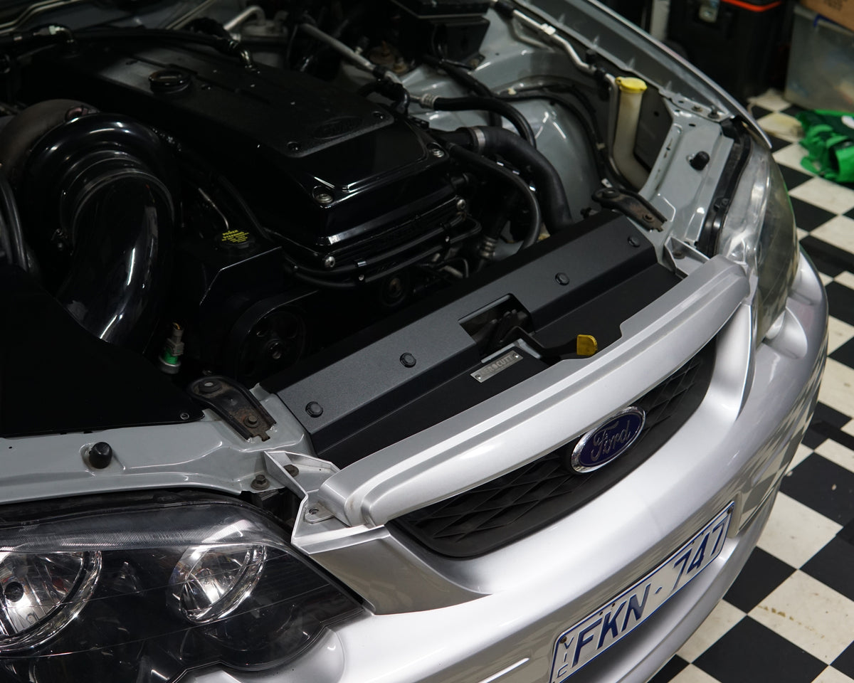 A close up of a Ford Falcon BA/BF engine bay with an Aerocutt aluminium replacment air diversion plate/cooling panel in powder coated black