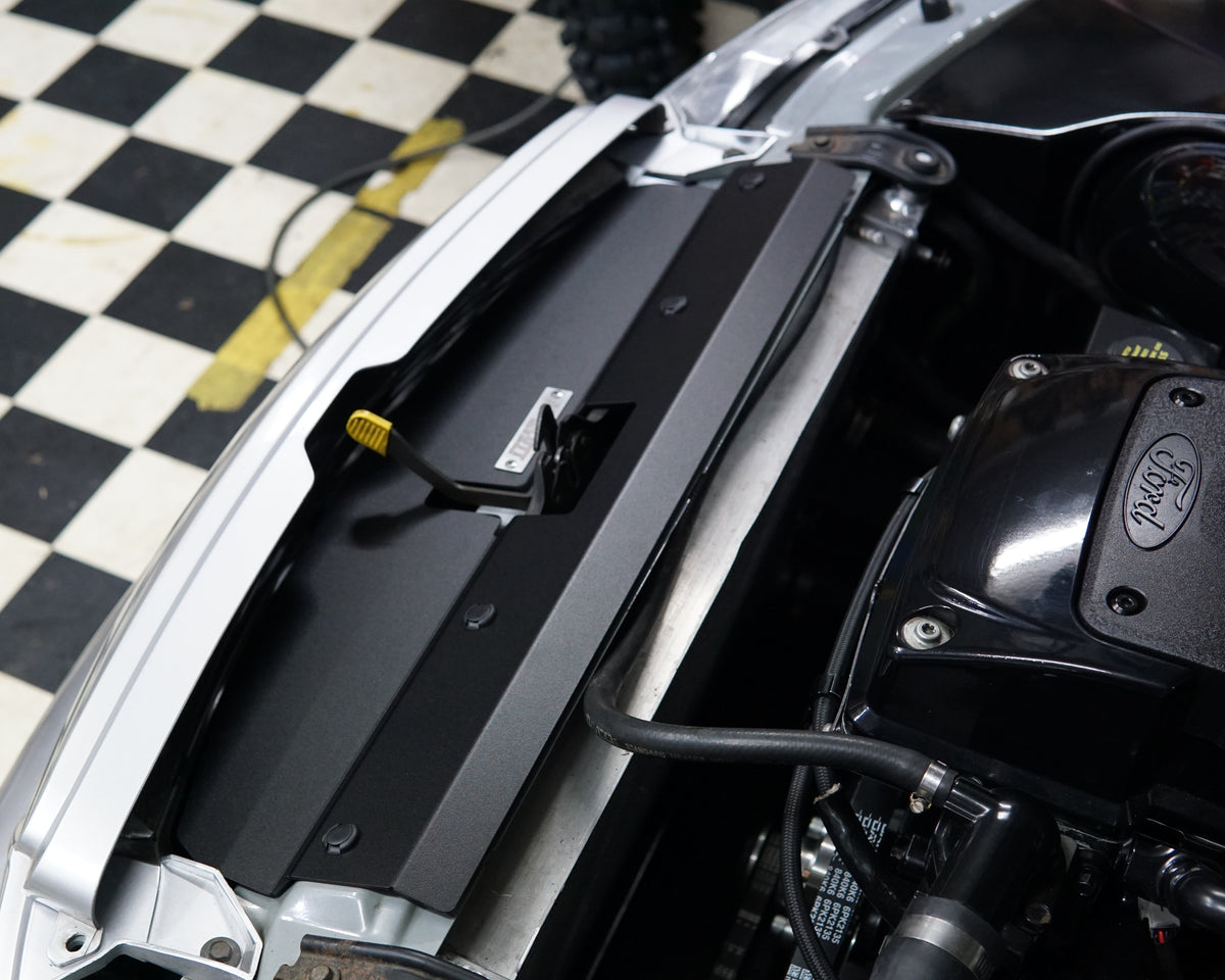 A close up of a Ford Falcon BA/BF engine bay with an Aerocutt aluminium replacment air diversion plate/cooling panel in powder coated black