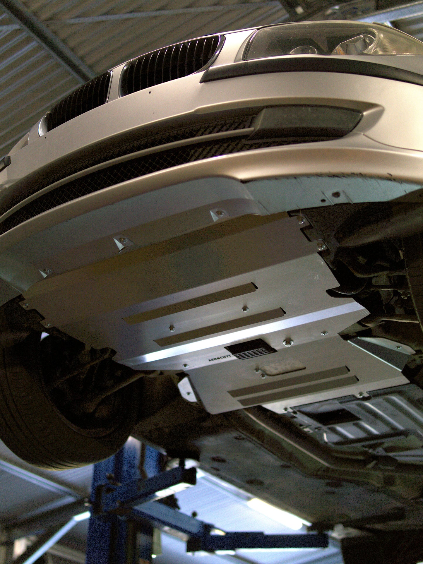 e87 bmw on a lift with undercarriage protection in a garage setting