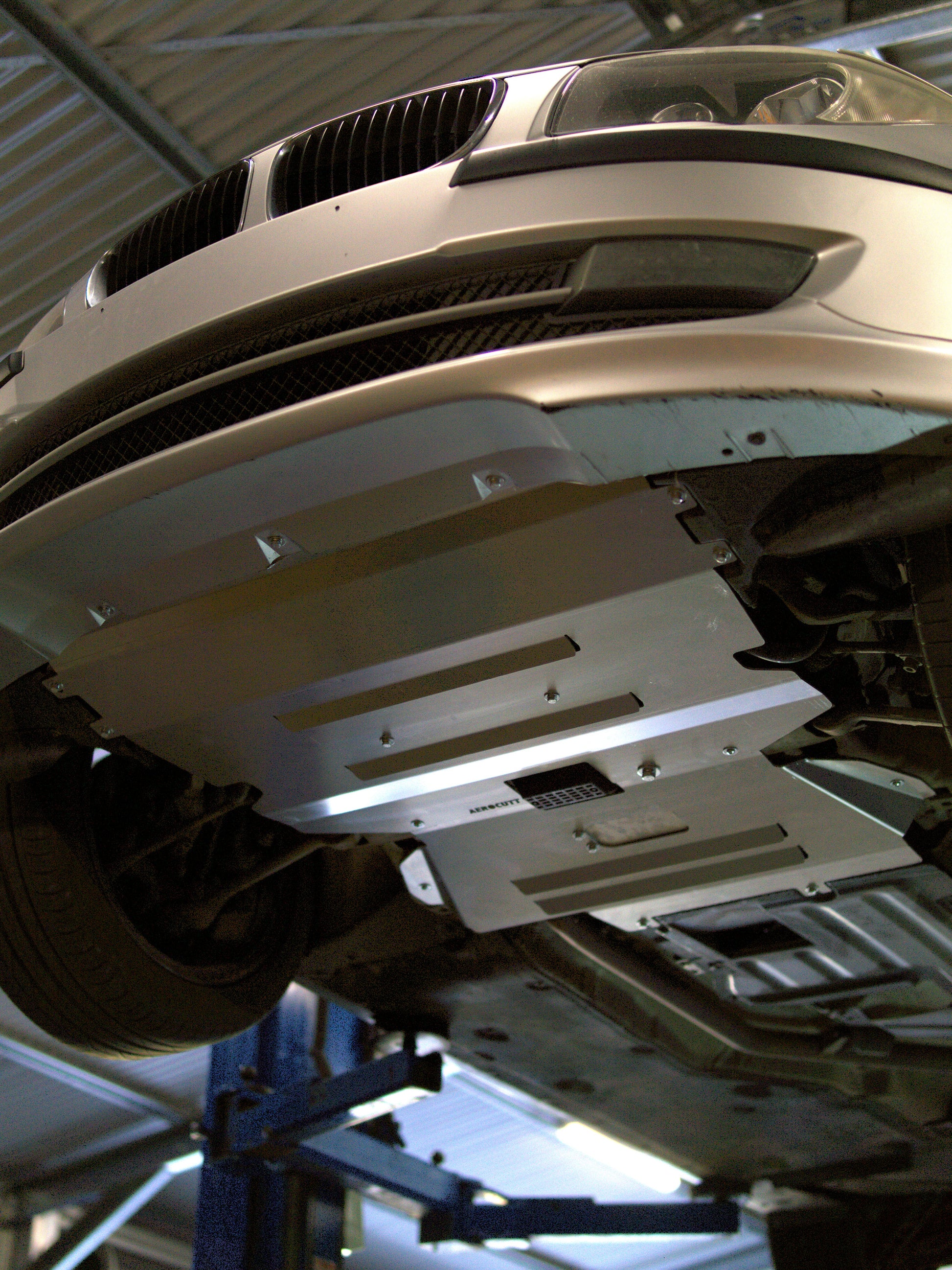 e87 bmw on a lift with undercarriage protection in a garage setting