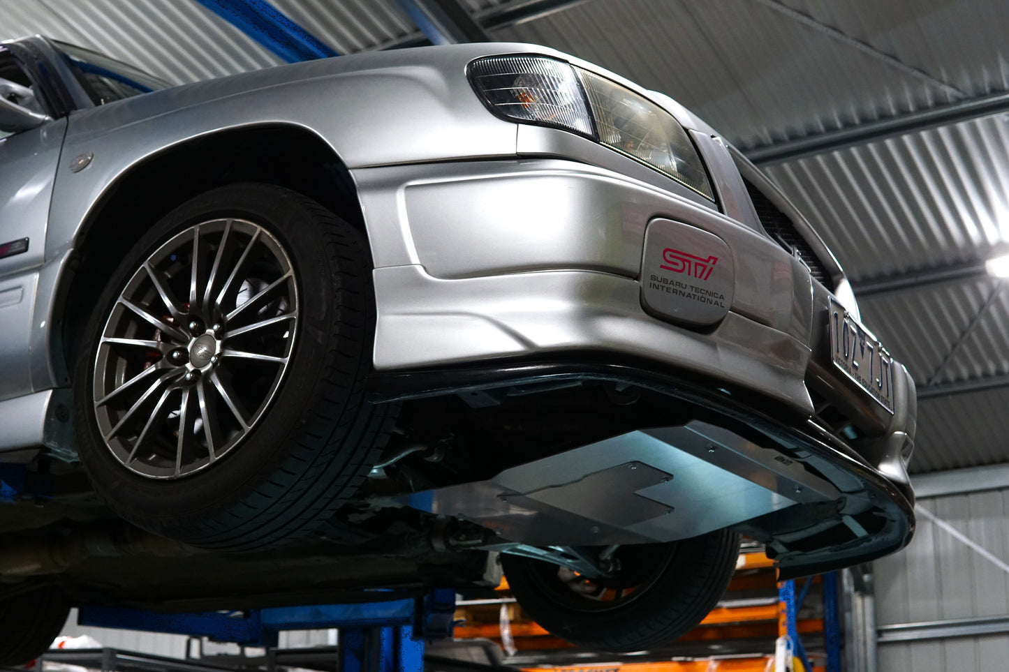 Silver car on a lift in a garage with underbody protection sump plate with aerocutt branding.