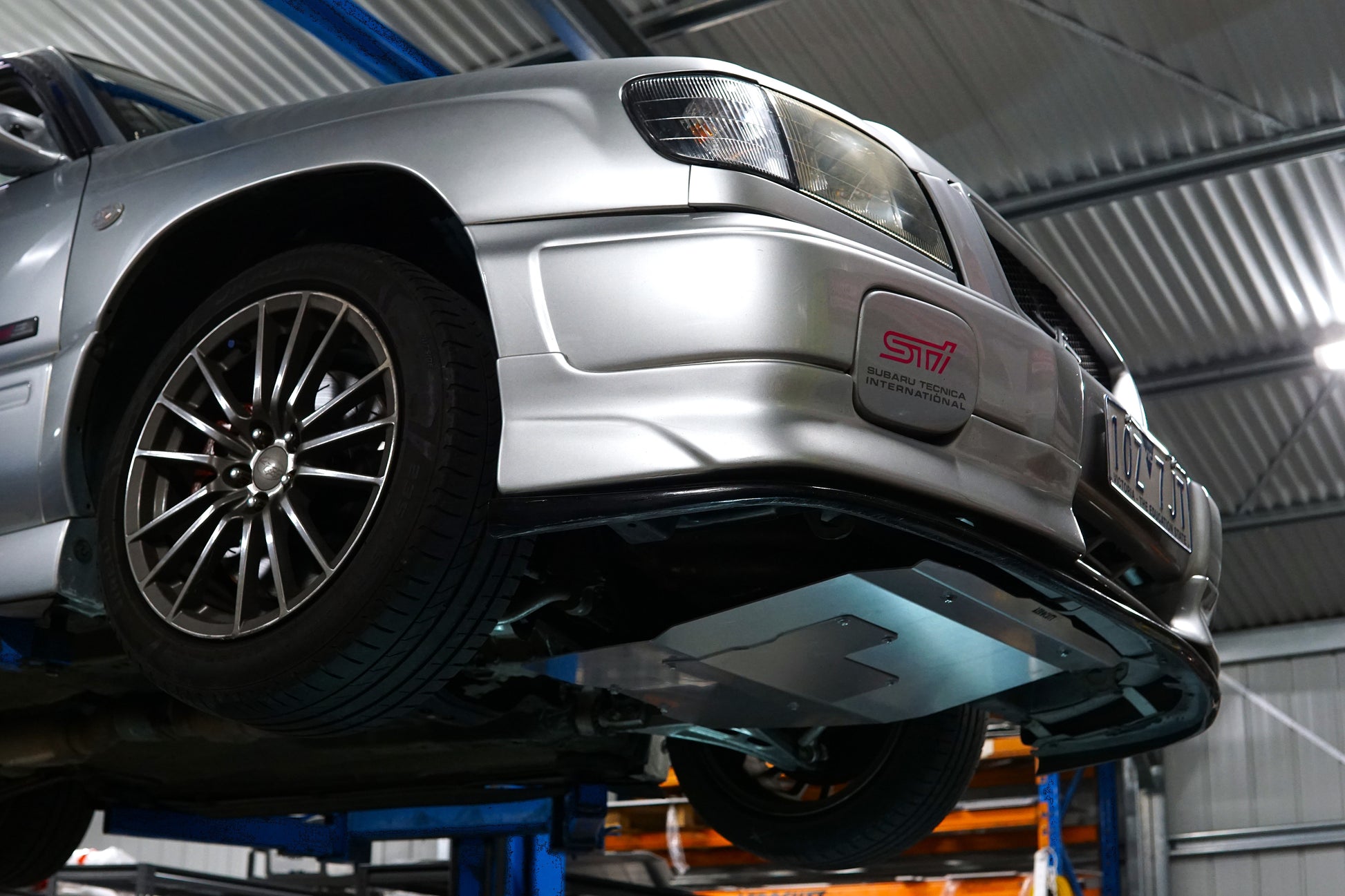 Silver car on a lift in a garage with underbody protection sump plate with aerocutt branding.