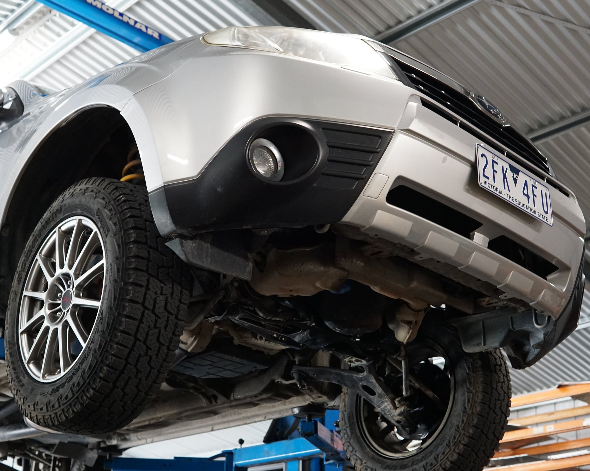 Underside of a Subaru Forester GT SH model on a lift having an Aerocutt skid plate installed